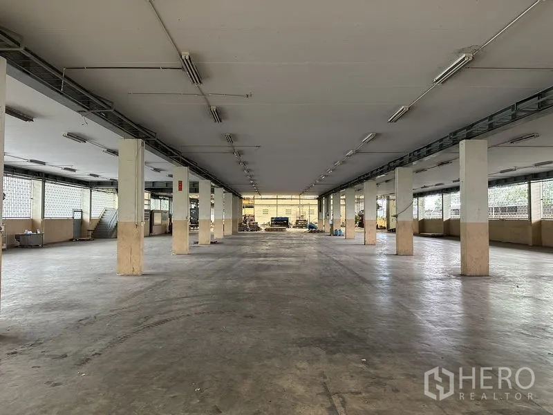 Factory for rent or sale in Lam Luk Ka, Pathum Thani - Long open-plan warehouse bay with pillars, fluorescent lighting and ventilation blocks.