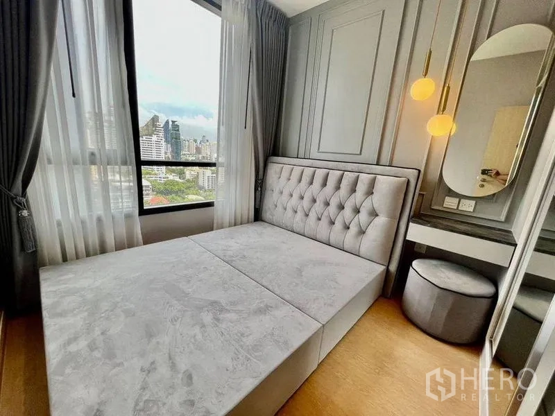 公寓 出租或出售在Watthana, Bangkok - 温馨卧室，绗缝床头板与吊灯，窗外尽览曼谷景色