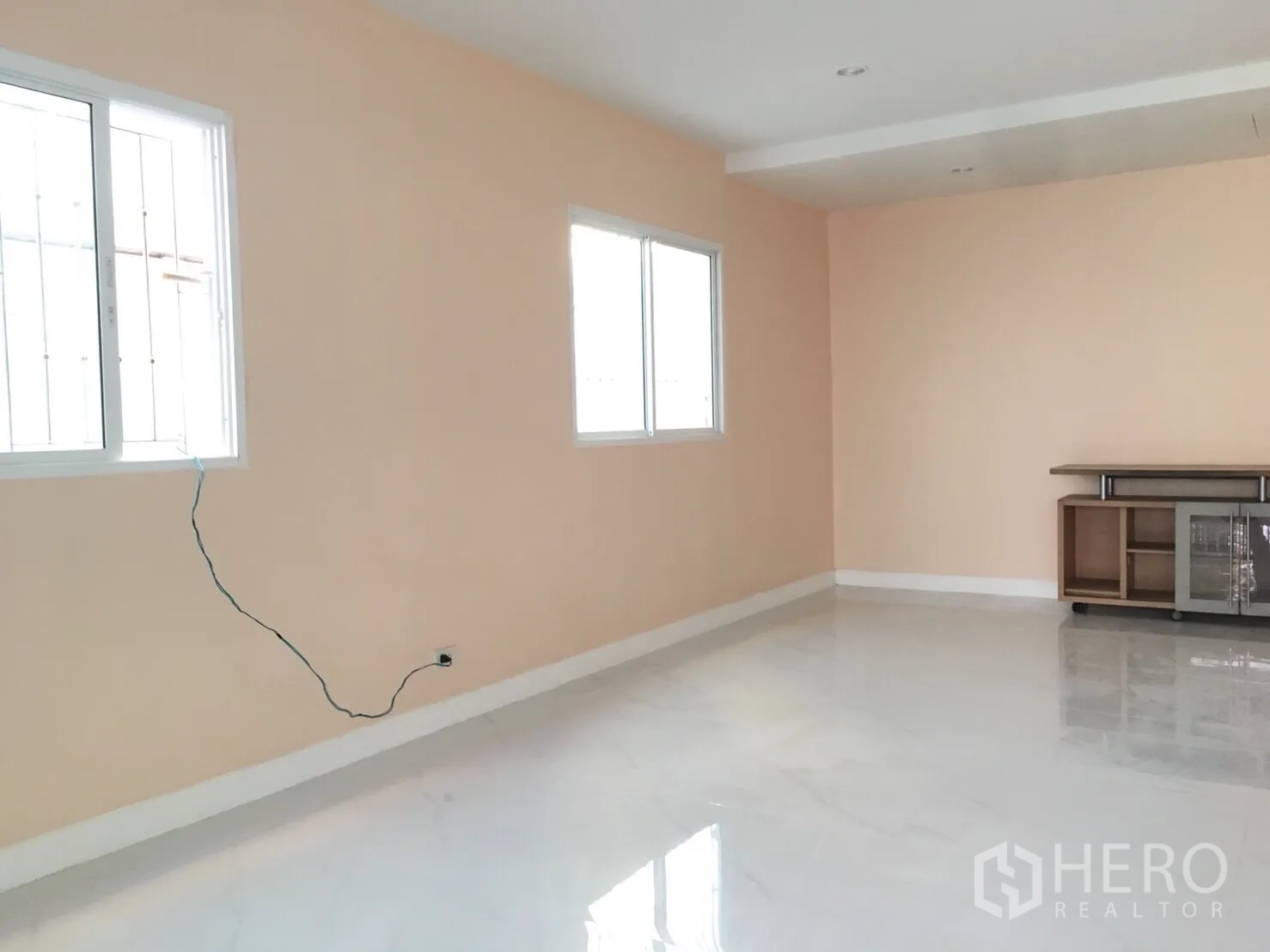 Townhouse for rent in Huai Khwang, Bangkok - Bright living area with peach walls, glossy white floor tiles and two windows.