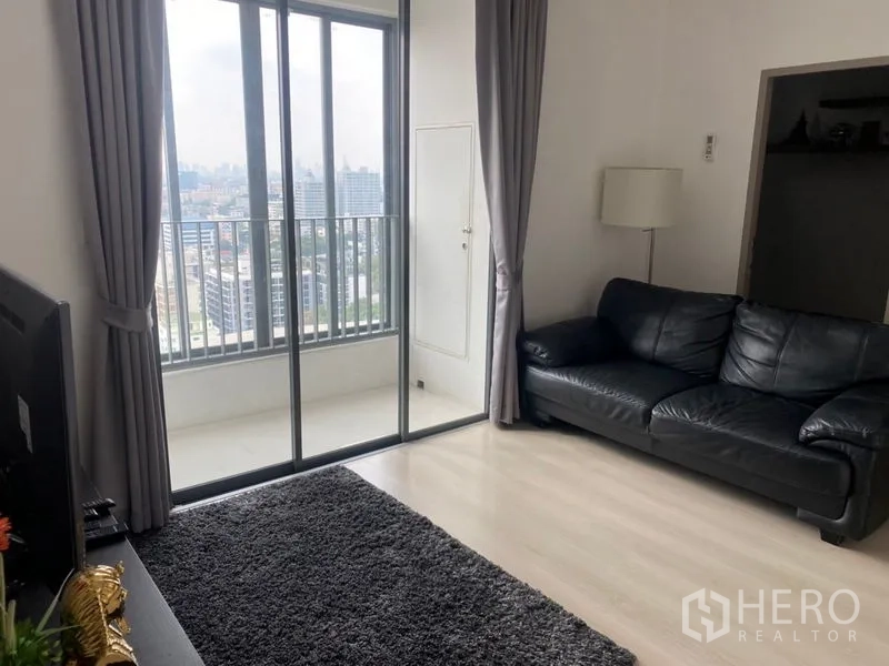 Condominium for sale in Phra Khanong, Bangkok - Balcony access through tall sliding doors facing the Bangkok skyline