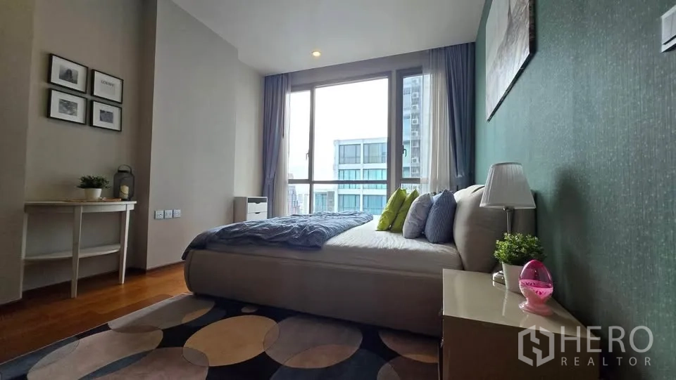 Condominium for rent in Watthana, Bangkok - Bedroom side view showing window, bedside table and city outlook.