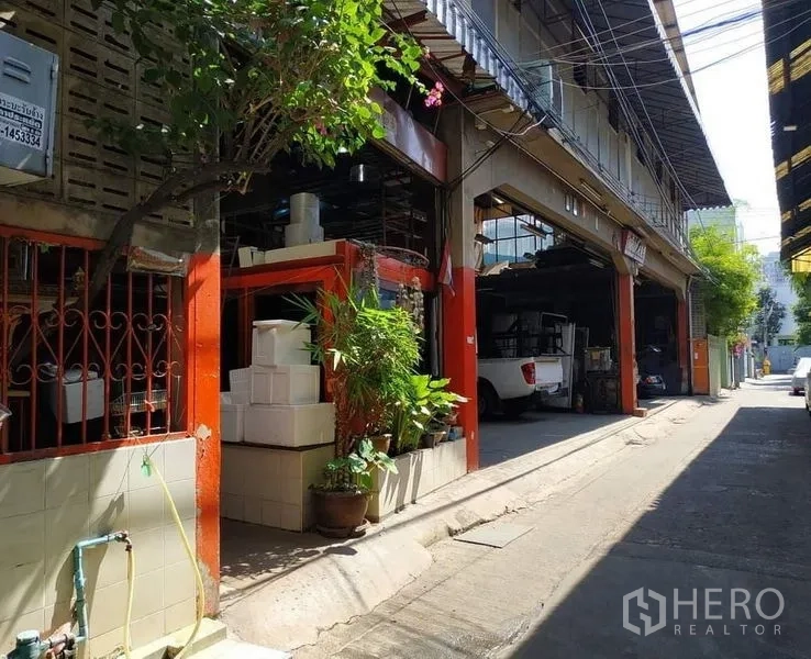 คลังสินค้า ให้เช่าในYan Nawa, Bangkok - ด้านข้างอาคารโกดัง เสาโทนส้ม กระถางต้นไม้ และทางเข้าออกในซอยย่านยานนาวา
