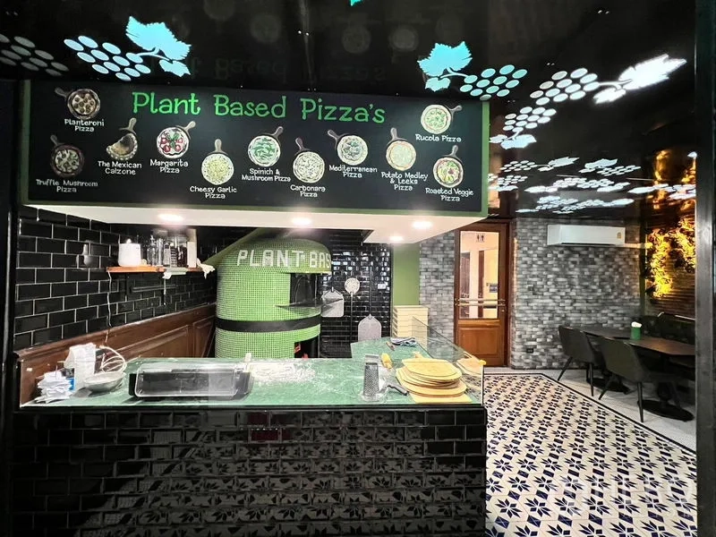 Shophouse for rent in Watthana, Bangkok - Open pizza station featuring a green-tiled oven, black subway tiles, and a menu board above the counter.