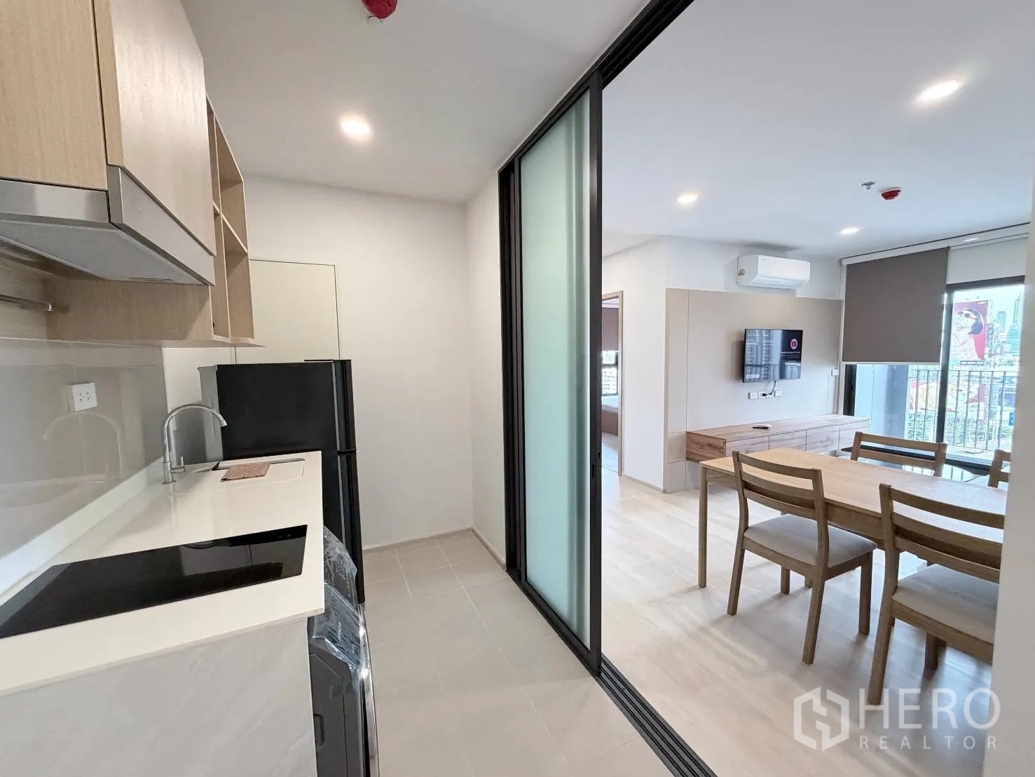 公寓 for rent in Din Daeng, Bangkok - 厨房以推拉玻璃门分隔，望向餐桌与带电视的客厅。