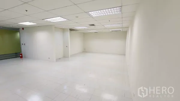 办公空间 出租在Watthana, Bangkok - 开放式办公布局，入口区域、柱位凹槽、天花灯具与亮面地砖，临玻璃立面