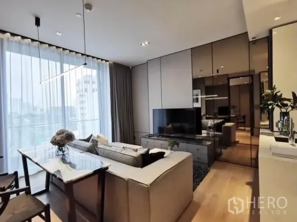 Condominium for rent in Khlong Toei, Bangkok - Living room with TV wall and dining table by full-height curtains