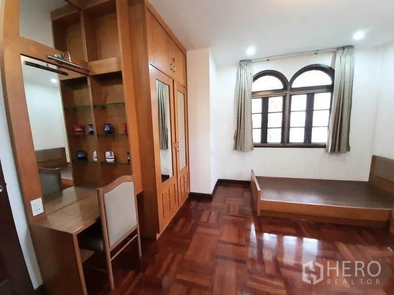 Detached House for rent in Watthana, Bangkok - Compact bedroom with built‑in shelving, dressing area and arched window.