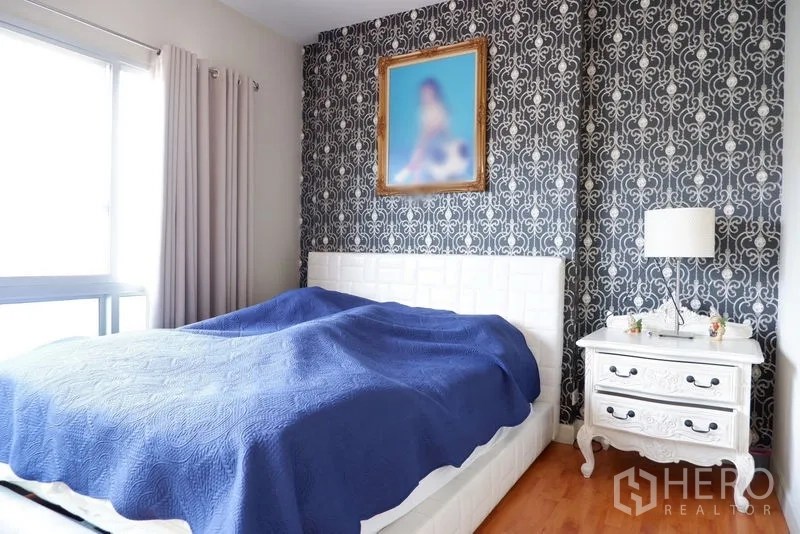 Detached House for sale in Saphan Sung, Bangkok - Cozy bedroom with patterned feature wall, white bed frame and bedside table.