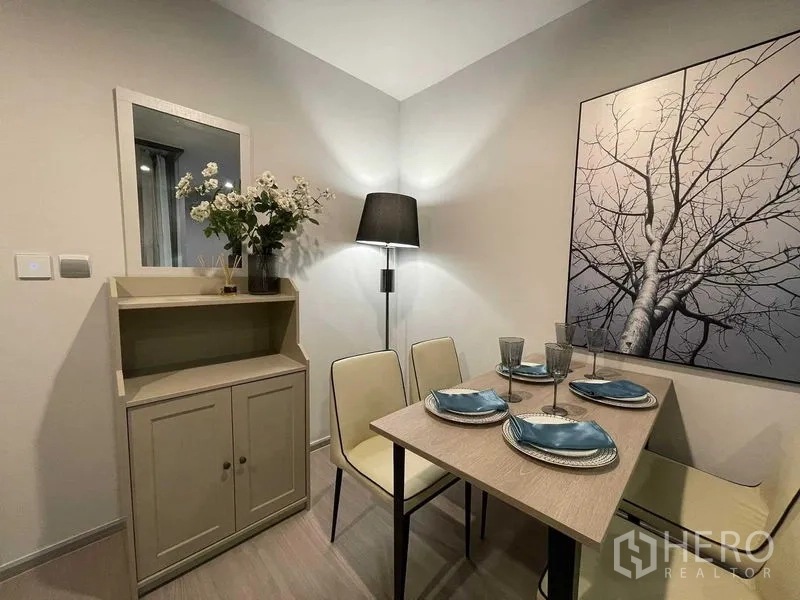 Condominium for rent in Chatuchak, Bangkok - Cozy dining corner with wall art, sideboard and floor lamp in neutral tones.