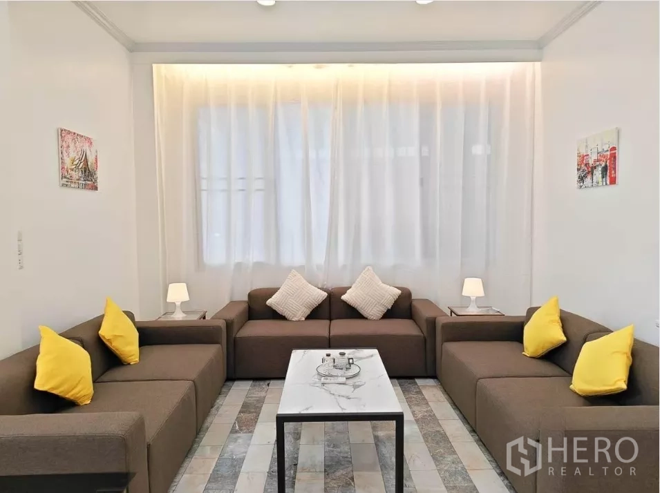 Detached House for rent in Yan Nawa, Bangkok - Cozy lounge area with U‑shaped sofas, marble coffee table, and sheer curtains.
