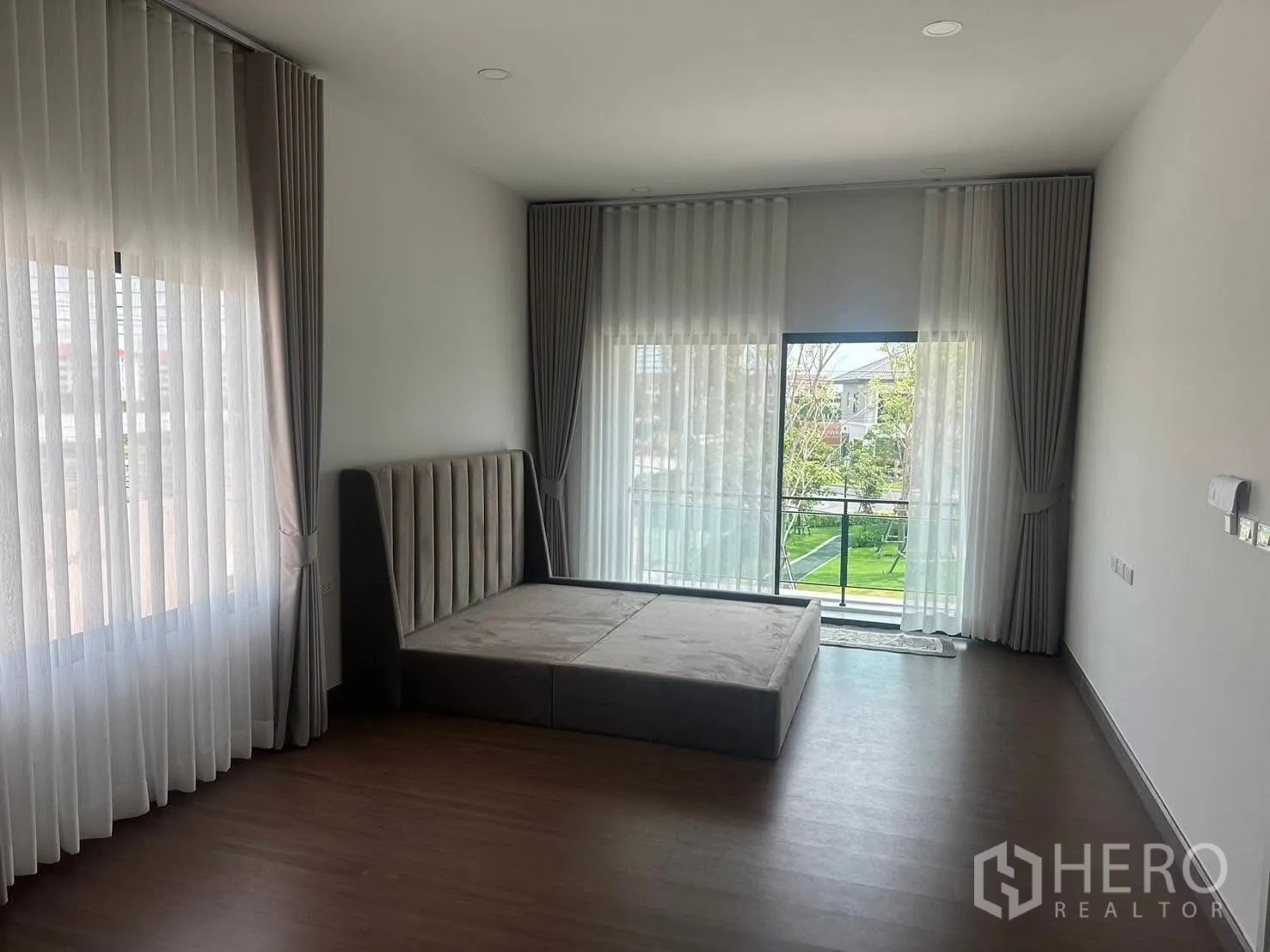Detached House for rent in Bang Phli, Samut Prakan - Spacious master bedroom with floor‑to‑ceiling windows, sheer curtains and a balcony overlooking green gardens.