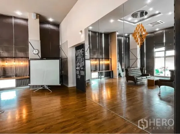 Office Space for rent in Lak Si, Bangkok - Bright open office with mirrored panels, seating nook, projector and tall windows with roller blinds on wood flooring.