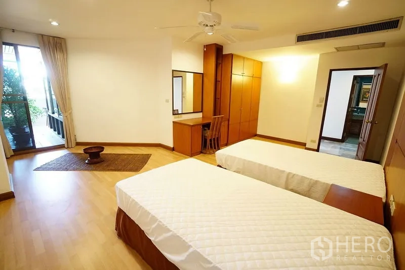 Apartment for rent in Watthana, Bangkok - Twin bedroom with two single beds, wardrobe and balcony doors.