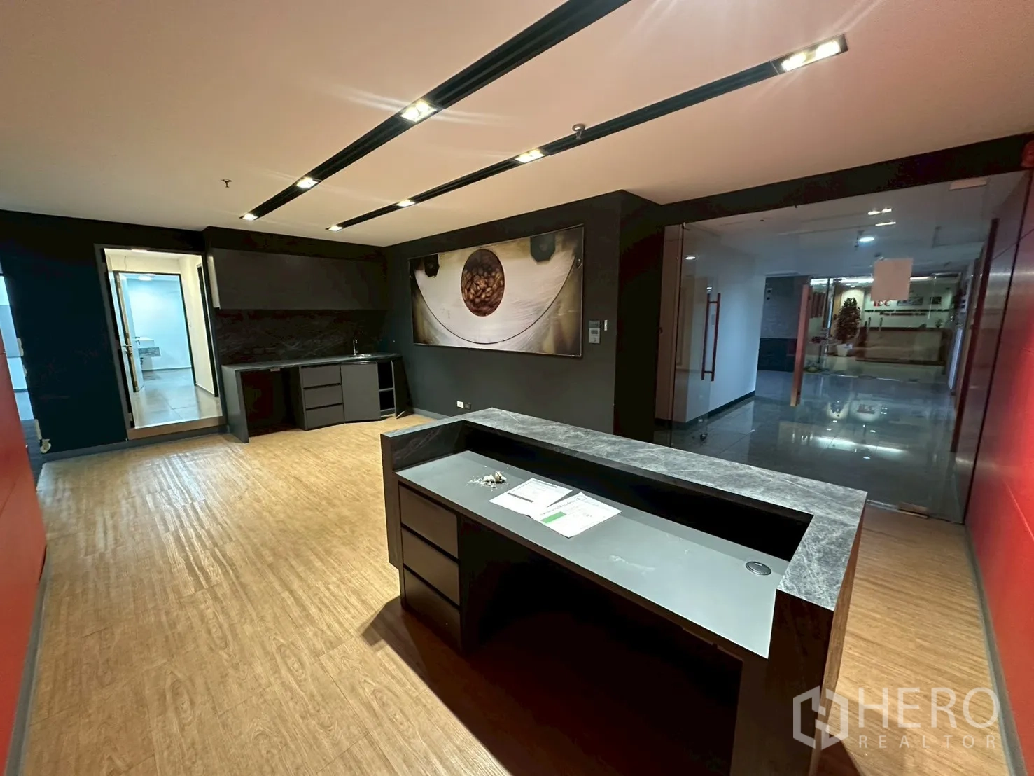 Office Space for rent - Reception facing a glass entrance with built-in pantry under sleek track lighting.