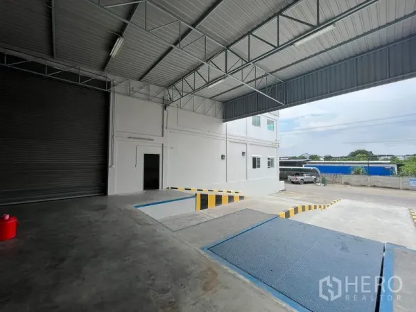 Warehouse for rent in Lat Krabang, Bangkok - Covered truck loading bay with dock leveler ramps, safety markings, and a roller shutter door at the warehouse entrance.