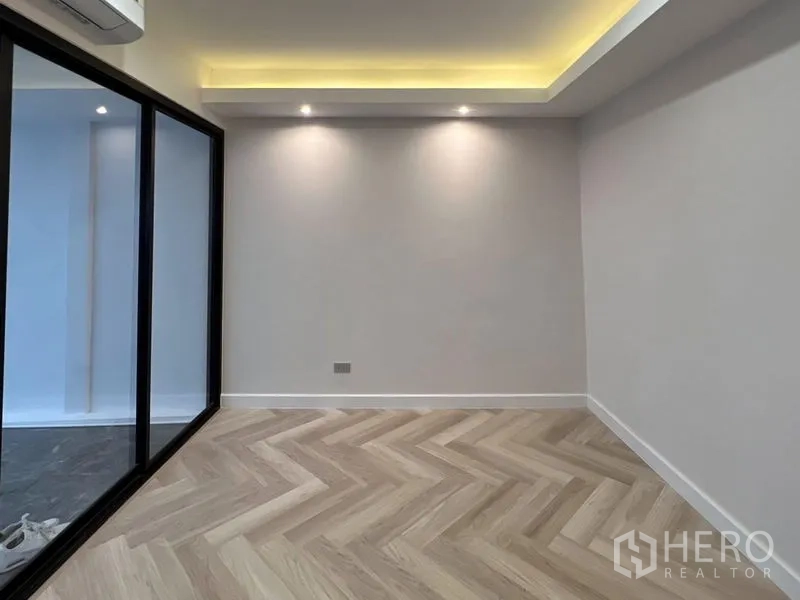Townhouse for rent or sale - Empty flex room with herringbone flooring, cove lights and a glass partition.