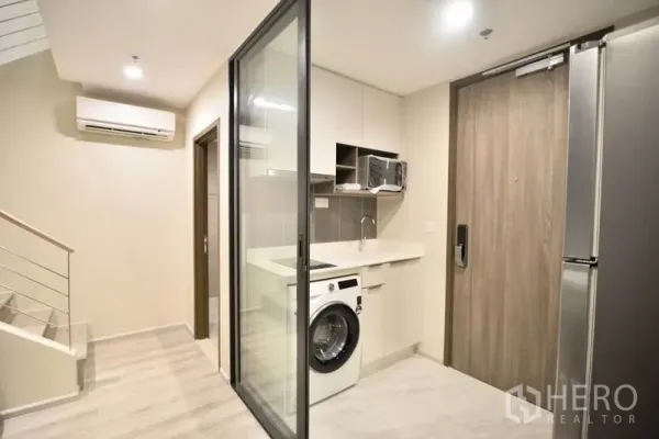 คอนโด ให้เช่าในHuai Khwang, Bangkok - โถงทางเข้าพร้อมครัวกั้นกระจก เครื่องซักผ้า และประตูไม้ในคอนโดสมัยใหม่