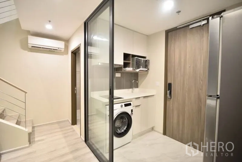 คอนโด ให้เช่าในHuai Khwang, Bangkok - โถงทางเข้าพร้อมครัวกั้นกระจก เครื่องซักผ้า และประตูไม้ในคอนโดสมัยใหม่