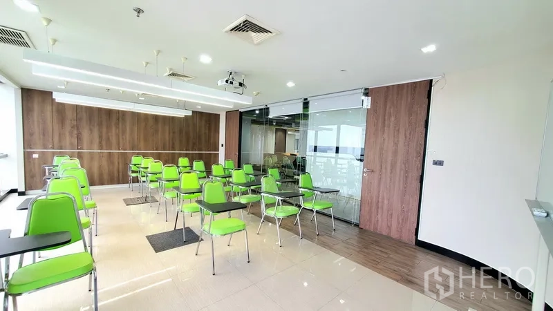 สำนักงาน ให้เช่าในWatthana, Bangkok - ห้องสัมมนาสว่าง เก้าอี้สีเขียว โปรเจ็กเตอร์ ประตูกระจกบานเลื่อนและผนังลายไม้