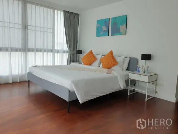Apartment for rent in Bang Rak, Bangkok - Airy bedroom with king bed, sheer curtains and warm hardwood floors.