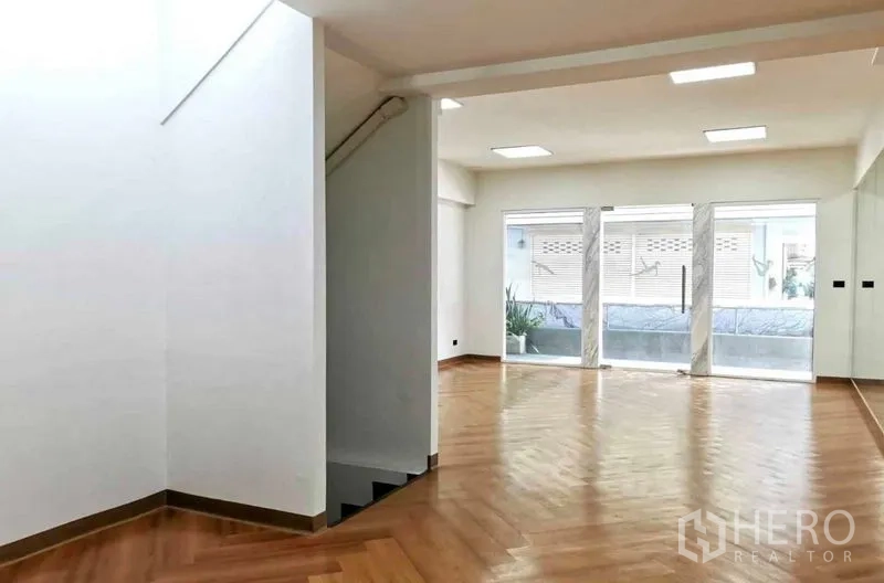 Home Office for rent in Watthana, Bangkok - Open-plan level showing a staircase, mirrored feature wall and wide glass doors leading to a terrace.
