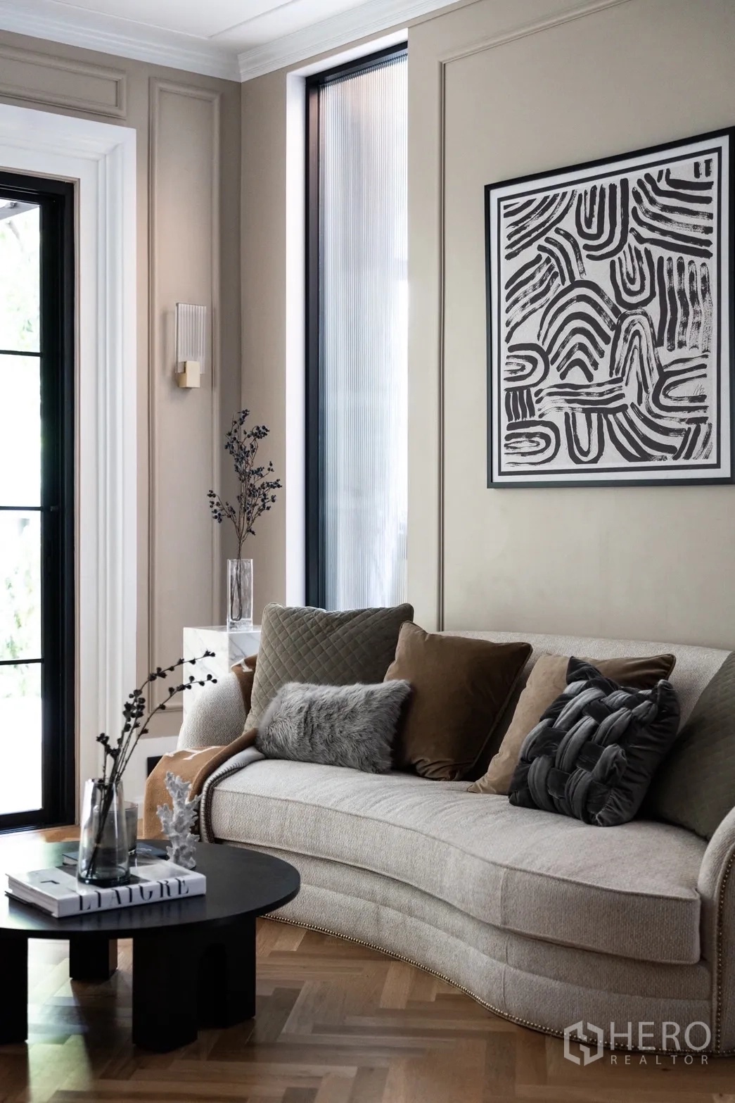Detached House for rent or sale in Phra Khanong, Bangkok - Stylish sitting area with curved sofa, art wall and side window.
