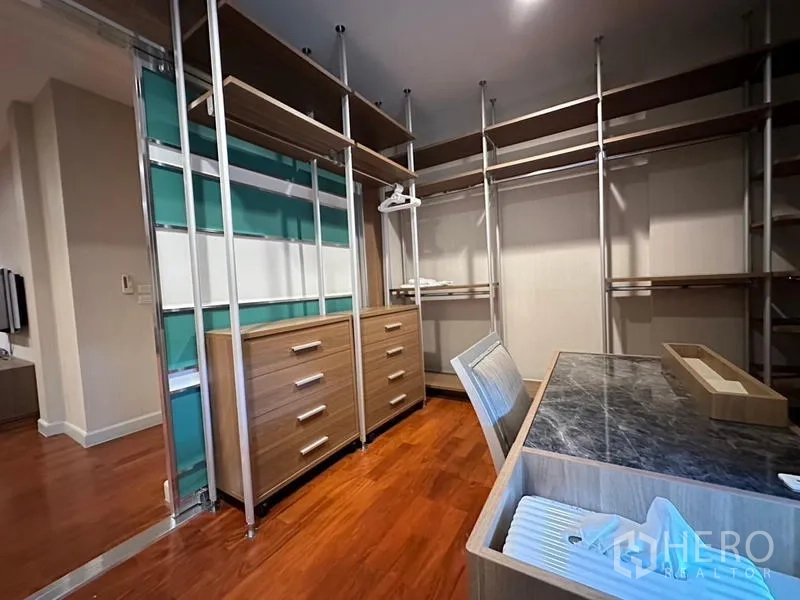 Detached House for rent or sale in Khan Na Yao, Bangkok - Dressing room with modular wardrobes, drawers and a marble-top desk.