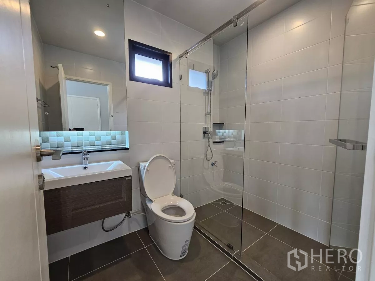 Detached House for sale in Lam Luk Ka, Pathum Thani - Contemporary bathroom with glass-enclosed shower, vanity and toilet.