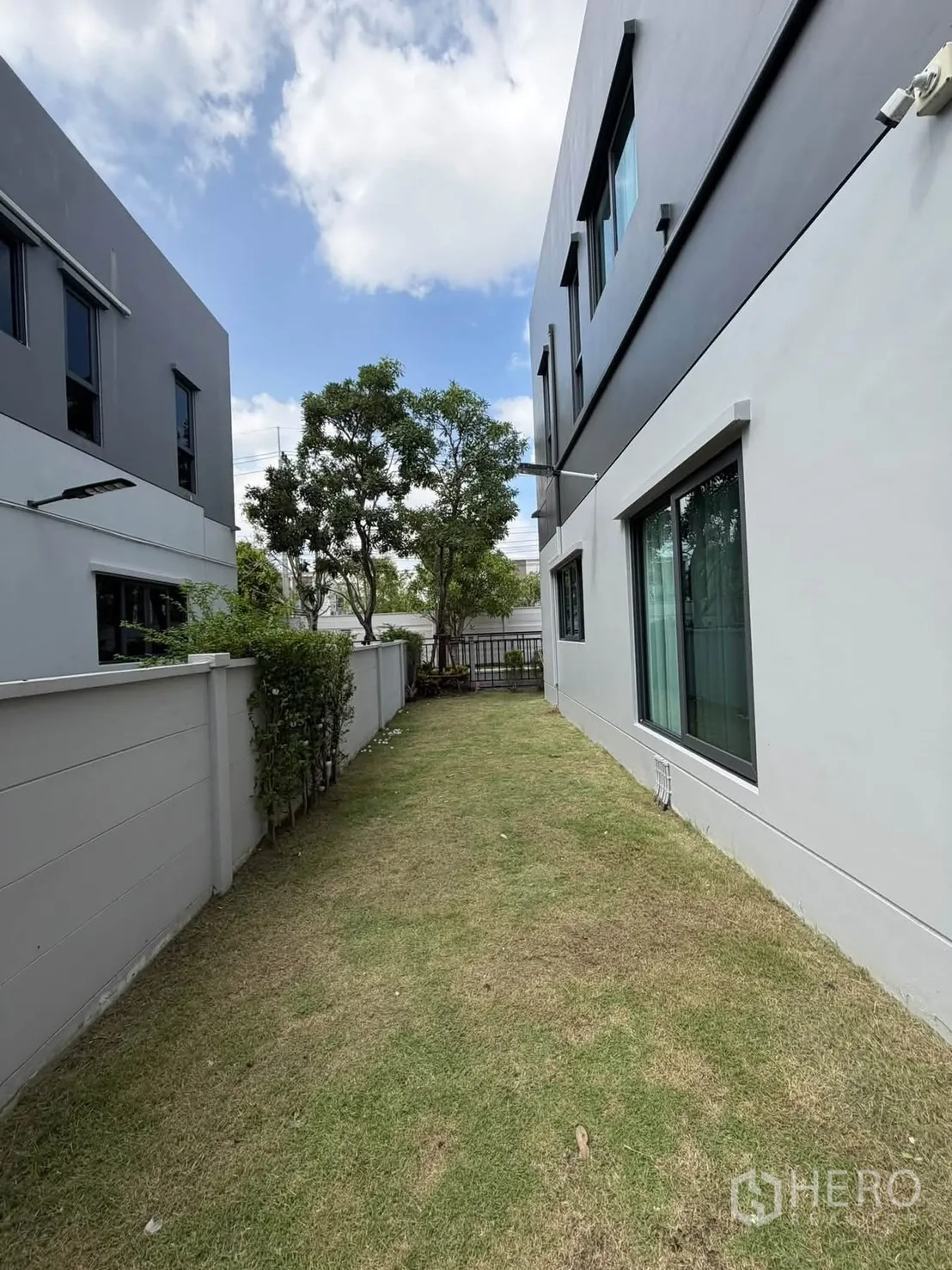 独栋房屋 for rent in Bang Phli, Samut Prakan - 房屋侧边的草坪花园与围墙通道。