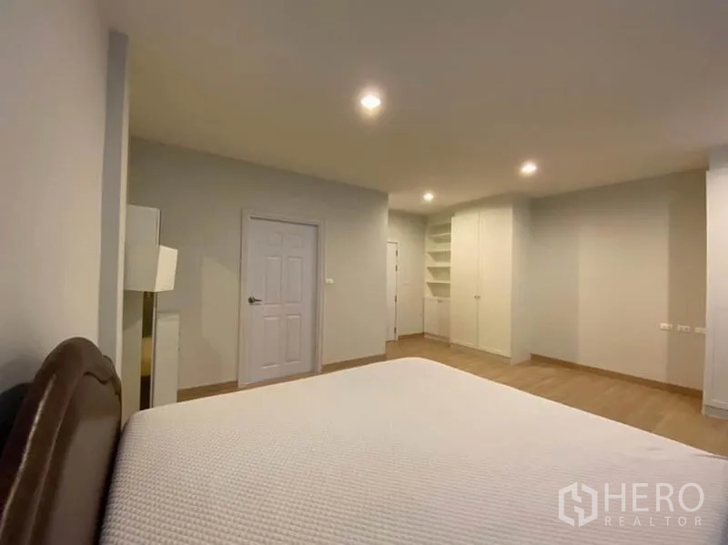 Townhouse for rent in Bang Na, Bangkok - Bedroom angle showing door, built‑in shelving, and wardrobe.