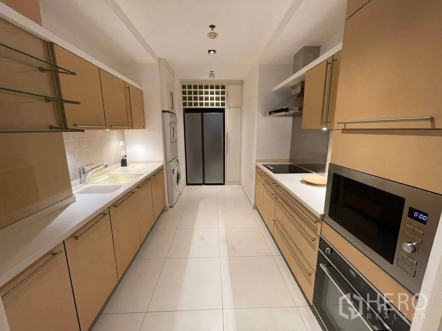 公寓 for rent in Pathum Wan, Bangkok - 走廊式厨房，浅木柜体配嵌入式烤箱、微波炉、灶台与双门冰箱。