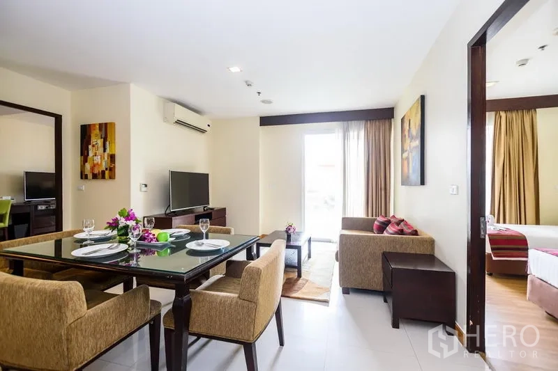 Condominium for rent in Khlong Toei, Bangkok - Bright open-plan living and dining area with sofa set, glass dining table, TV console and a balcony door at Lohas Residences Sukhumvit.