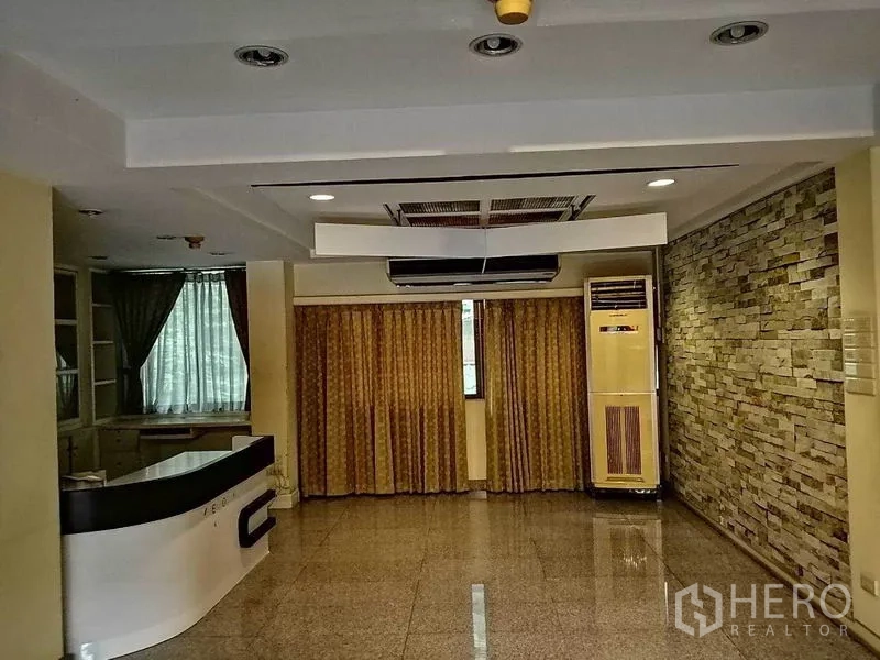 办公空间 出租在Khlong Toei, Bangkok - 接待区带石材特色墙、内置接待台、窗帘与天花空调。