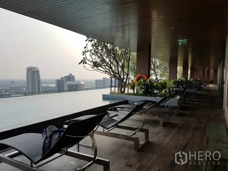 公寓 出租在Watthana, Bangkok - 泳池畔遮蔽平台与躺椅，毗邻无边际泳池。