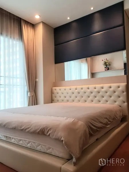 Condominium for rent in Khlong Toei, Bangkok - Second bedroom featuring a tufted headboard, floor-to-ceiling curtains and soft lighting.