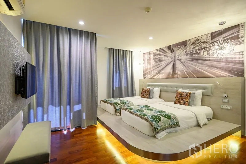 公寓 出租在Pathum Wan, Bangkok - 抬高平台上的双床卧室，配图形壁面与遮光窗帘