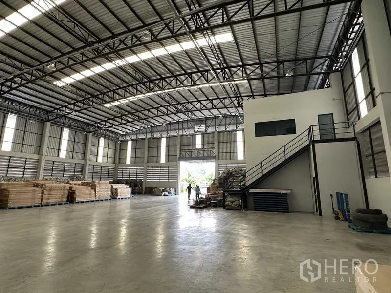 Warehouse for rent in Bang Phli, Samut Prakan - Clear-span warehouse floor with steel roof structure and stair access to the mezzanine office.