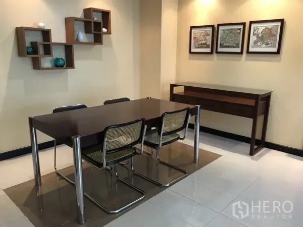 公寓 出租在Watthana, Bangkok - 用餐区，深色餐桌四椅，墙面置物架与装饰画。