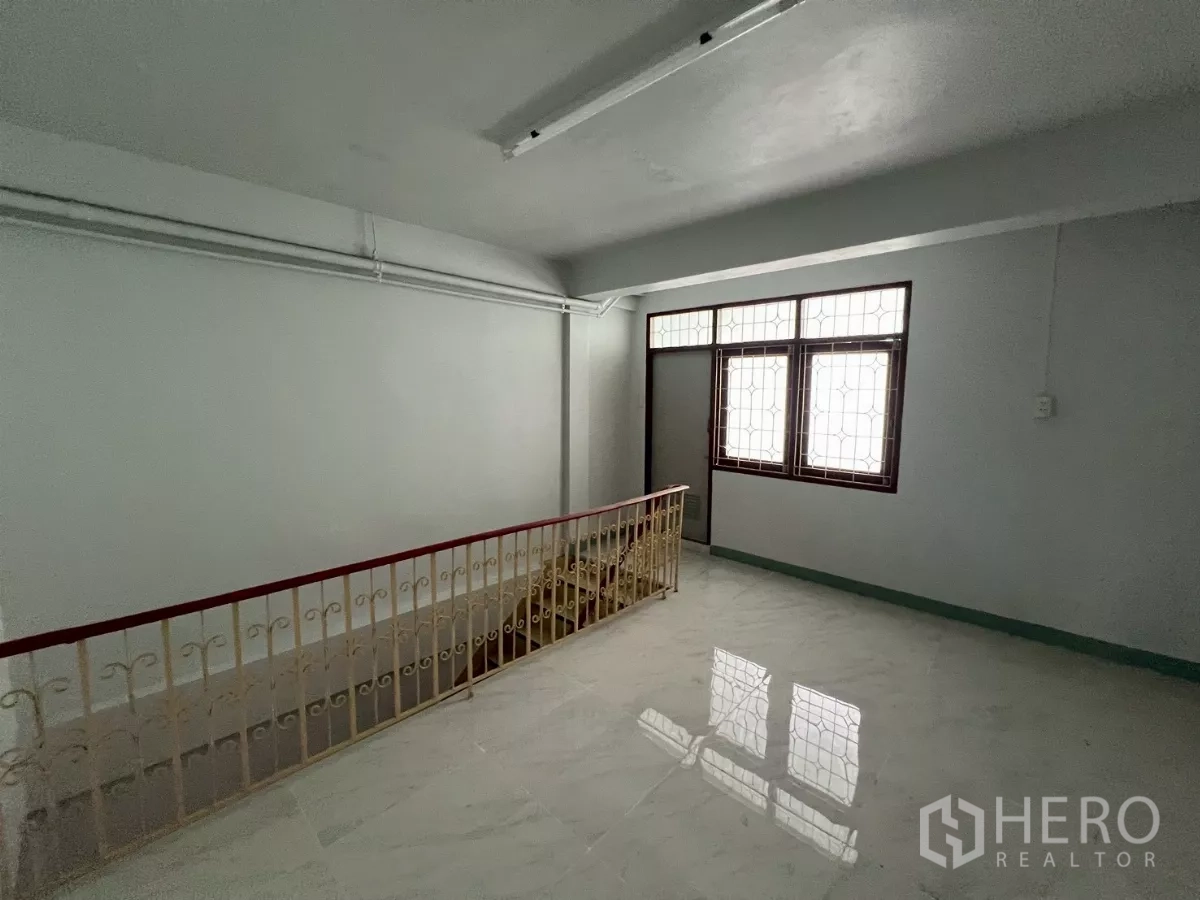Shophouse for rent in Khlong Toei, Bangkok - Upper landing area with window, tiled floor and stair rails.