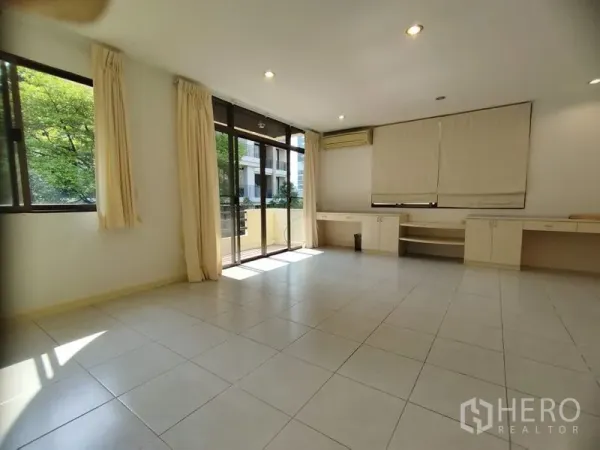Detached House for rent in Watthana, Bangkok - Spacious room with built-in desks, tile flooring, and balcony doors.