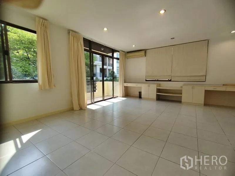 Detached House for rent in Watthana, Bangkok - Spacious room with built-in desks, tile flooring, and balcony doors.