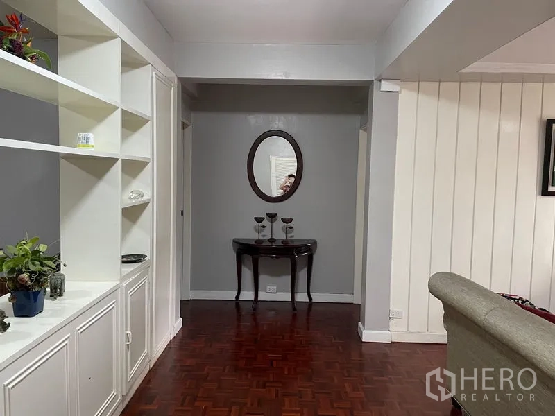 Condominium for rent in Watthana, Bangkok - Hallway with built-in shelving units and a console table with round mirror.