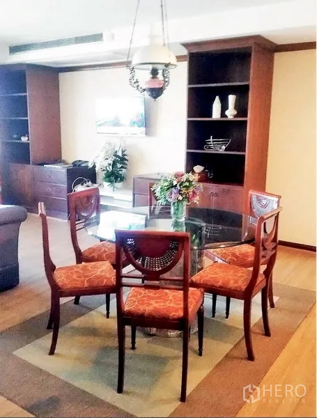 Condominium for rent or sale in Watthana, Bangkok - Glass-top dining table for four under a pendant light, flanked by built-in bookshelves.