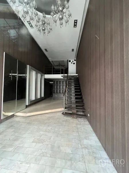 店屋 出租在Watthana, Bangkok - 挑高店面内饰，带夹层、楼梯与吊灯，木纹墙面和石材地面