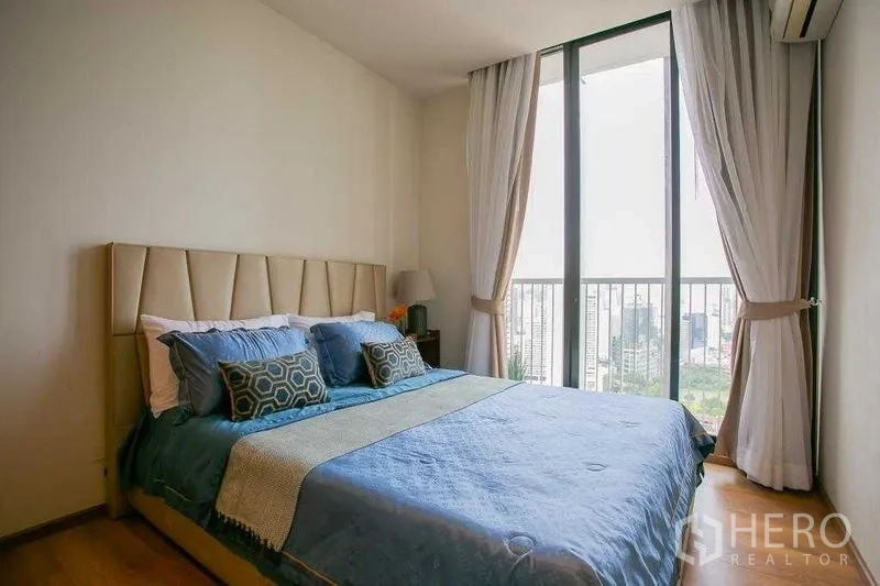 Condominium for sale in Khlong Toei, Bangkok - Master bedroom with king bed, large window, curtains, and city views.