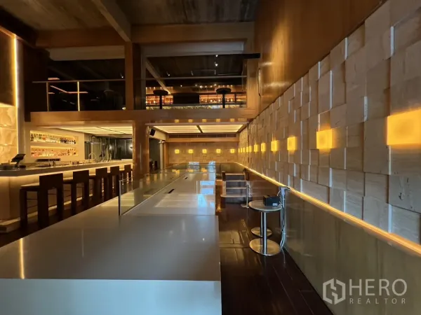 零售空间 出租在Watthana, Bangkok - 长吧台与灯光点缀的立体墙面及卡座。