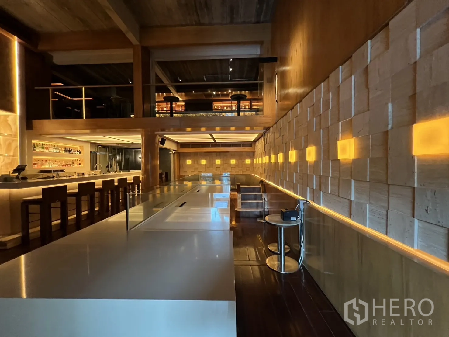 零售空间 出租在Watthana, Bangkok - 长吧台与灯光点缀的立体墙面及卡座。