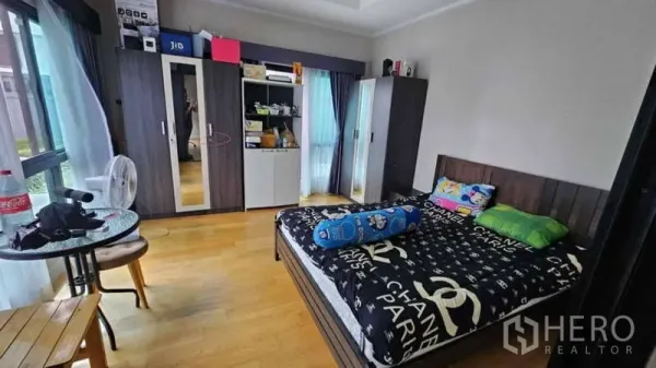 Detached House for rent or sale in Prawet, Bangkok - Bright bedroom with wood floors, large windows, built-in wardrobes and a queen bed.