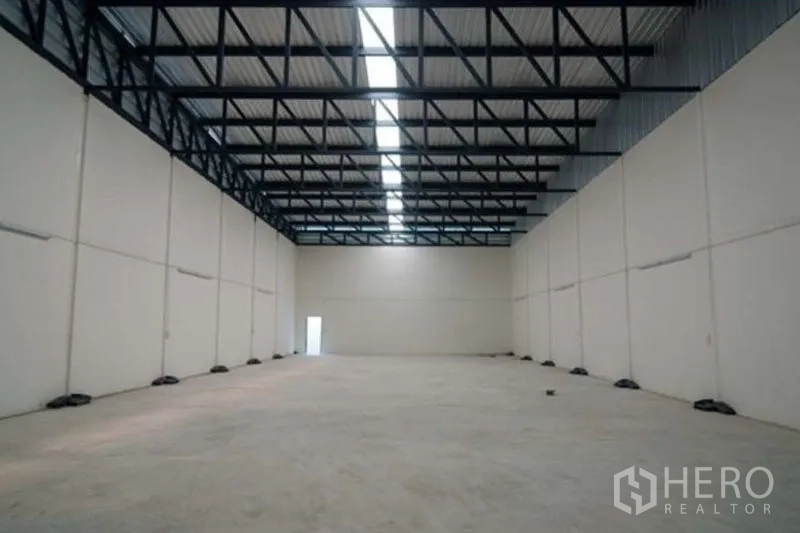 Factory for rent in Bang Sao Thong, Samut Prakan - High-ceiling warehouse hall with steel trusses and a central skylight.