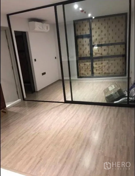 Condominium for sale in Khlong Toei, Bangkok - Open-plan room with sliding glass divider, recessed lighting, and covered floor-to-ceiling window.